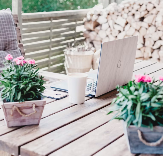 white coffee cup and laptop with plants on a table