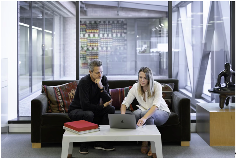 two people on a couch discussing something and focusing on a laptop